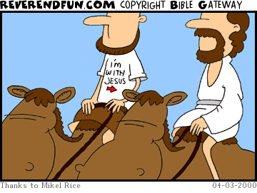 DESCRIPTION: Two men riding on camels, one with &quot;I'm with Jesus&quot; shirt on CAPTION: 